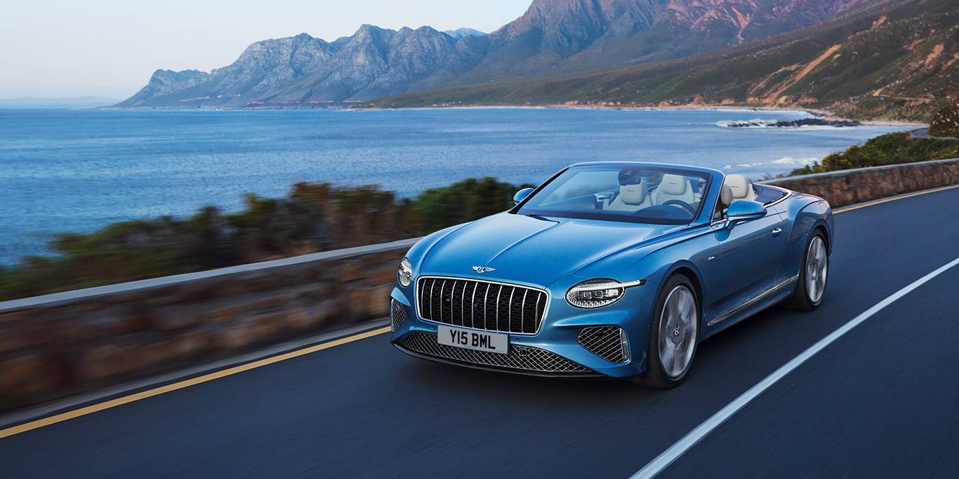 Bentley Katowice New Bentley Continental GTC Azure convertible in Light Windsor blue paint with 22 inch Azure wheels and chrome grill, driving dynamically by the sea