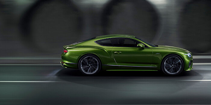  Bentley Katowice Bentley Continental GT coupe in Tourmaline Green paint driving in profile on a dark road