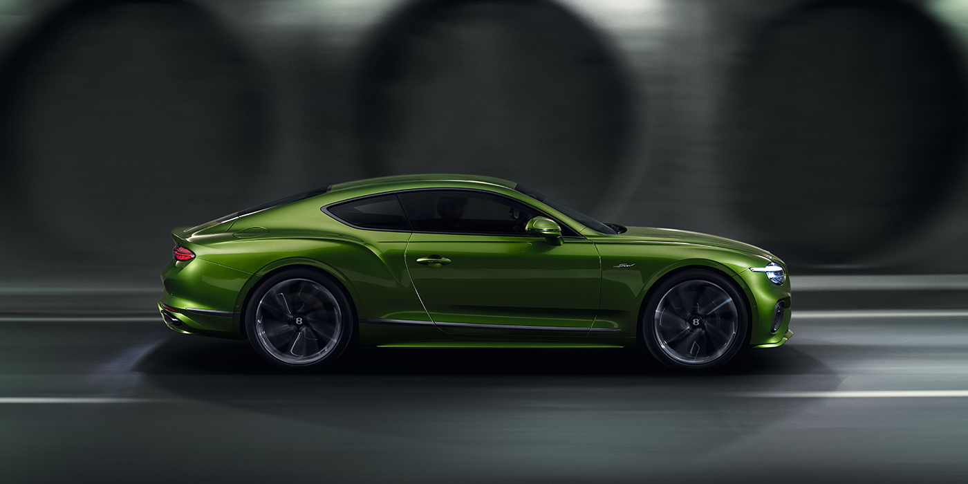 Bentley Katowice Bentley Continental GT coupe in Tourmaline Green paint driving in profile on a dark road